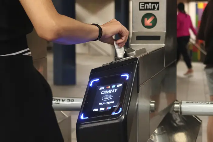 A person swipes in with a Metrocard at a turnstile outfitted with an OMNY touchpad at the Columbus Circle - 59th Street subway station.